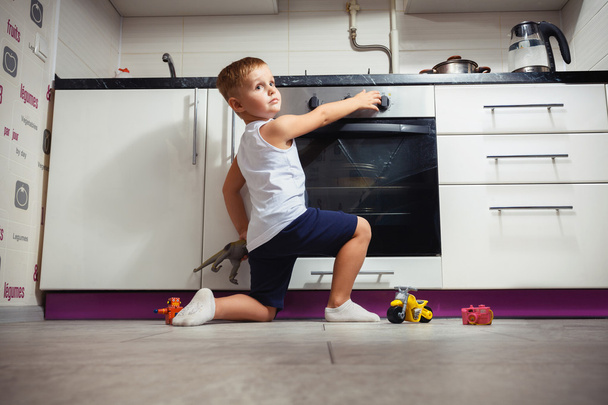 dziecko bawiąc się w kuchnia gazowa. - Zdjęcie, obraz