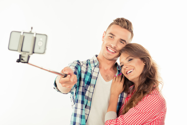 Cheerful couple in love making selfie photo with selfie stick - Fotó, kép