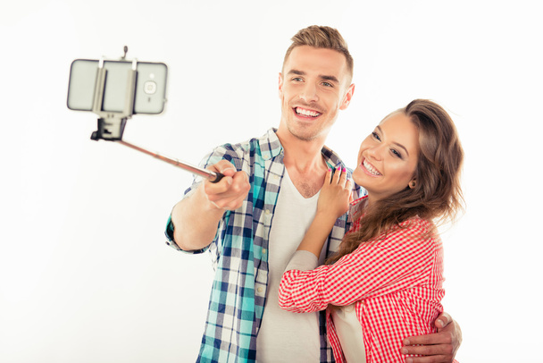 Cheerful cute couple in love making selfie photo with selfie sti - Fotó, kép