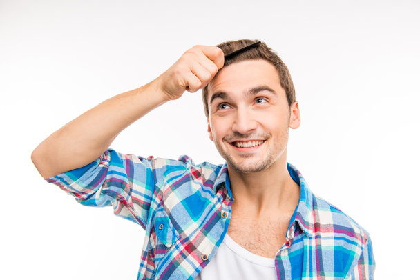 Handsome happy young man combing his hair - Fotografie, Obrázek