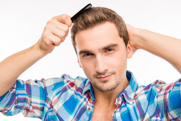 Handsome cheeky young man combing his hair - Foto, Bild