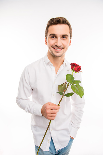 Ρομαντικό όμορφος άντρας δίνει ένα κόκκινο τριαντάφυλλο - Φωτογραφία, εικόνα