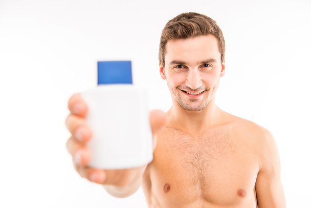 Handsome young man holding lotion after shave  - Фото, зображення