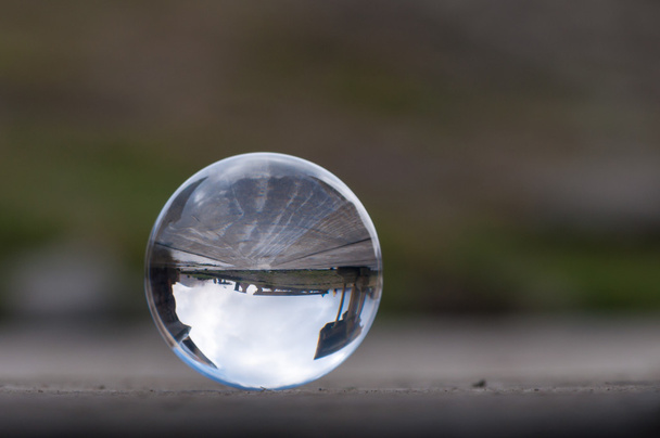 Üveg átlátszó kristály labda sötétzöld háttér és fa felülettel. Lágy fókusz. A üres hely a szöveg - Fotó, kép
