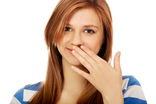 Teenage woman giggles covering her mouth with hand - 写真・画像