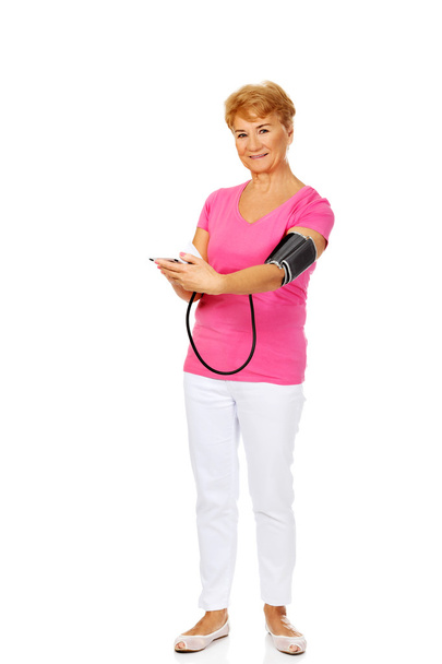 Smiling senior woman measuring blood pressure - Foto, imagen