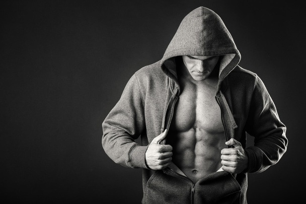 М'язистий чоловік у спортивній куртці на темному тлі
 - Фото, зображення
