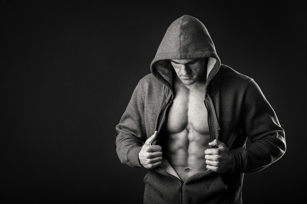 Muscular man in a sports jacket on a dark background - Fotó, kép