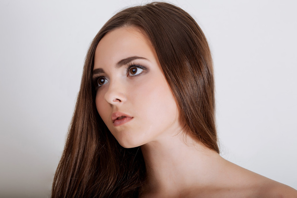 Young brunette lady with a beautiful hair on gray background - Foto, Imagem