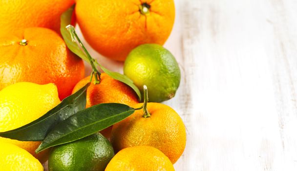Fresh citrus fruits with leaves on wooden background - 写真・画像