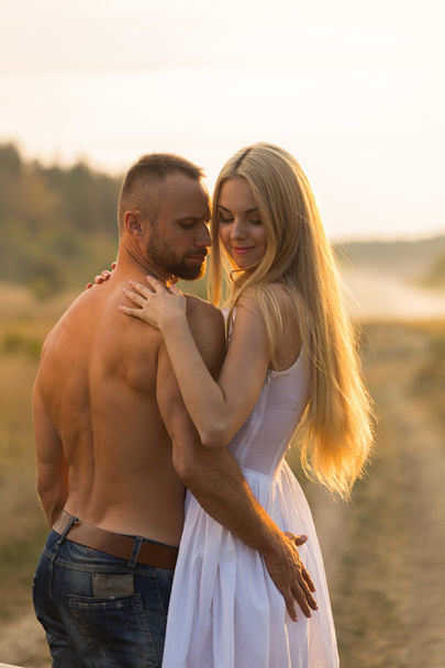 Muscular man with a beautiful woman on a motorcycle middle of a field road - Fotoğraf, Görsel