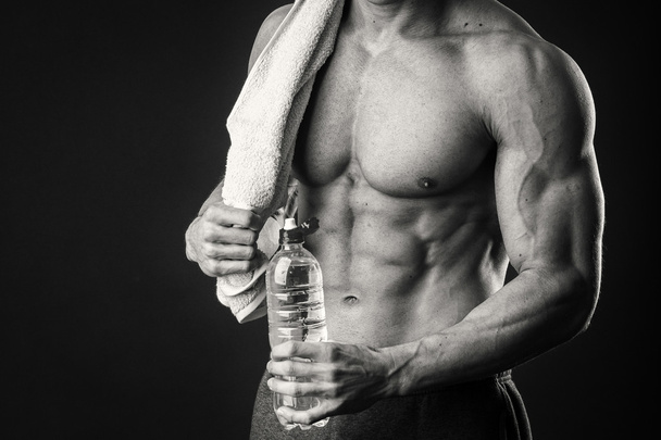 Muscular man with a towel in his hands on a dark background - Foto, afbeelding