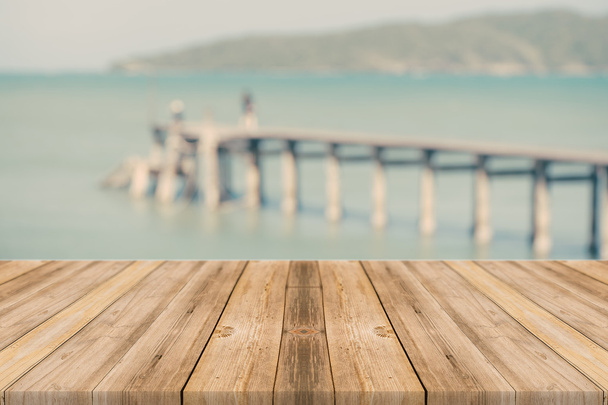 Piano in legno su fondo mare azzurro sfocato e spiaggia di sabbia bianca, tono vintage - utilizzabile per esporre o montare prodotti
 - Foto, immagini