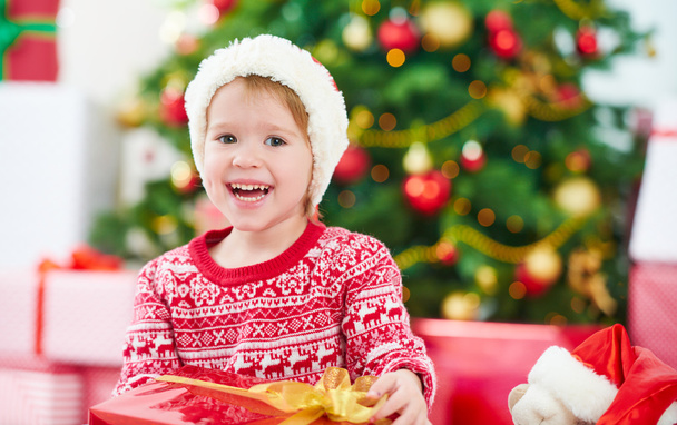glückliches Kind mit Weihnachtsgeschenken in der Nähe eines Weihnachtsbaums - Foto, Bild