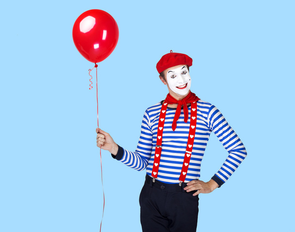 Mime with balloon.Emotional funny actor wearing sailor suit, red beret posing on blue background. - 写真・画像