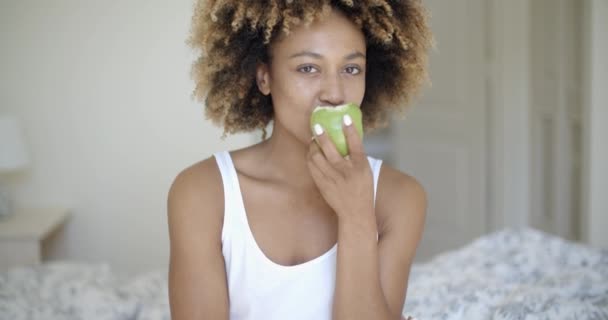 kobieta siedziała na łóżku i jabłko jedzenie - Materiał filmowy, wideo