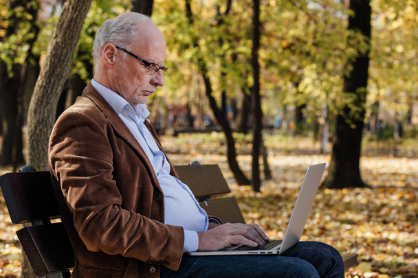 old businessmen working at laptop outside on a bench - Fotoğraf, Görsel