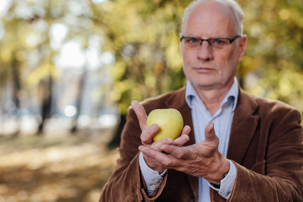 senior adult holding green apple - Foto, afbeelding