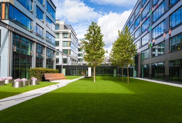 Moderno parque de escritórios com gramado verde, árvores e banco
 - Foto, Imagem