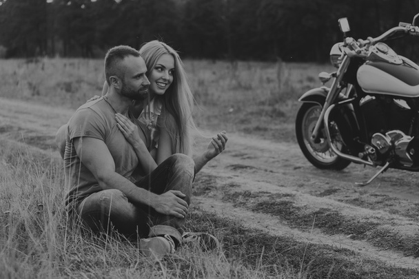 Мускулистый мужчина с красивой женщиной на мотоцикле посреди полевой дороги
 - Фото, изображение