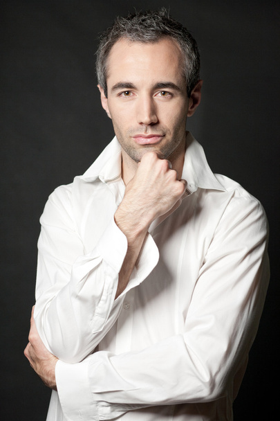 Man posing in white shirt on dark background in studio. - Valokuva, kuva