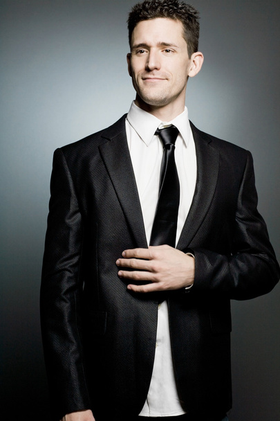 Hombre de negocios guapo en traje negro expresando positividad
. - Foto, Imagen