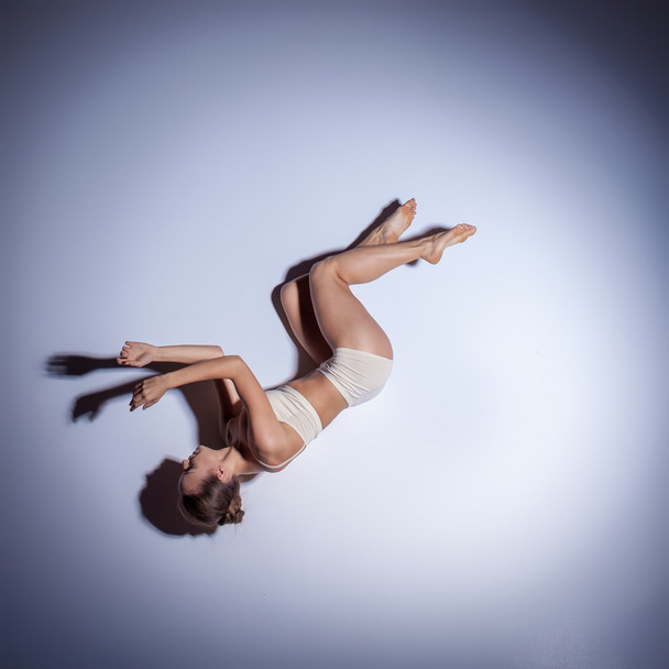 Young beautiful dancer in beige swimwear dancing on lilac background - Valokuva, kuva