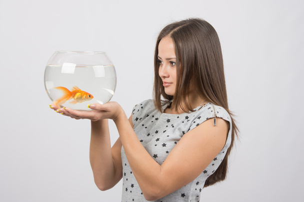 A young girl looks at a goldfish - Foto, imagen