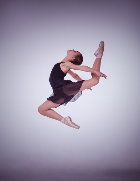 The silhouette of young ballet dancer jumping on a lilac  background. - 写真・画像