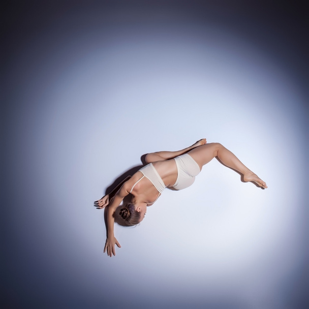 Young beautiful dancer in beige swimwear dancing on lilac background - Fotografie, Obrázek