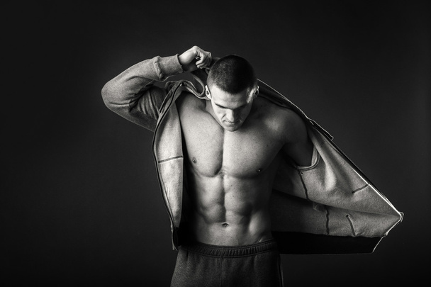 Muskularny mężczyzna w sportowa Kurtka na ciemnym tle - Zdjęcie, obraz