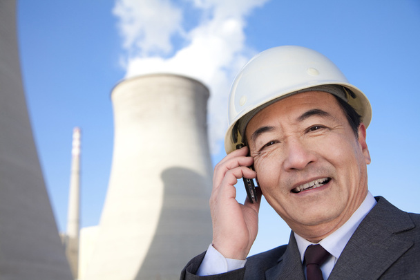 Businessman on mobile phone at power plant - Photo, Image
