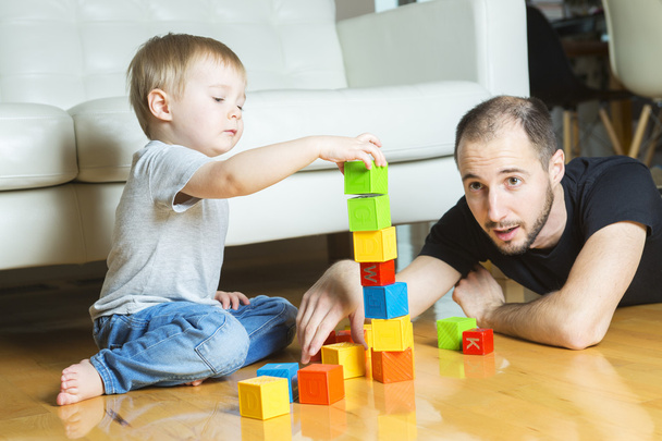 vader spelen blok met zijn zoon thuis - Foto, afbeelding