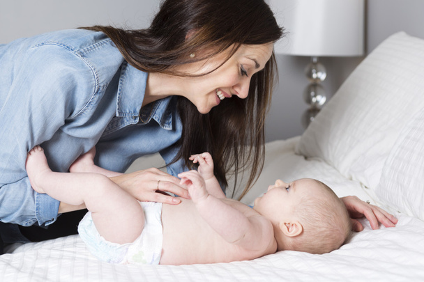 mother with baby on bed having fun - Photo, Image
