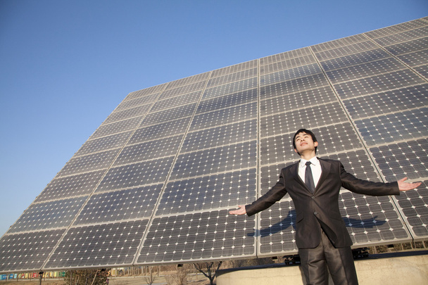 Homme d'affaires avec les bras tendus devant les panneaux solaires
 - Photo, image