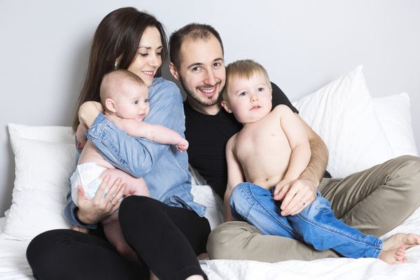 happy family on white bed in the bedroom - Fotó, kép
