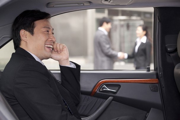 Бізнесмен розмовляє по телефону в машині
 - Фото, зображення