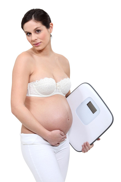 A pregnant woman with a scale. - Фото, изображение