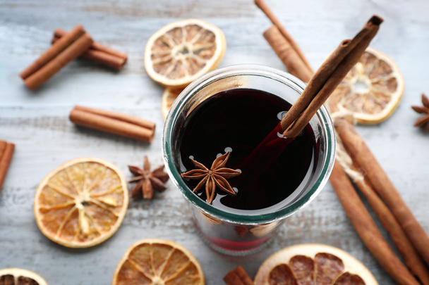 Tasty mulled wine and spices, on blue wooden background, close-up - 写真・画像