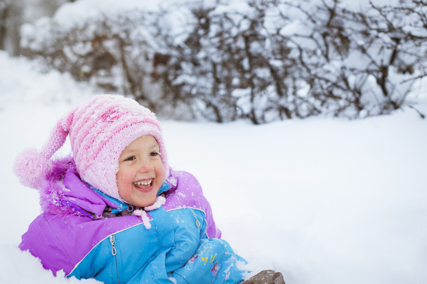 Cheerful little girl playing with snow in Park - Photo, image