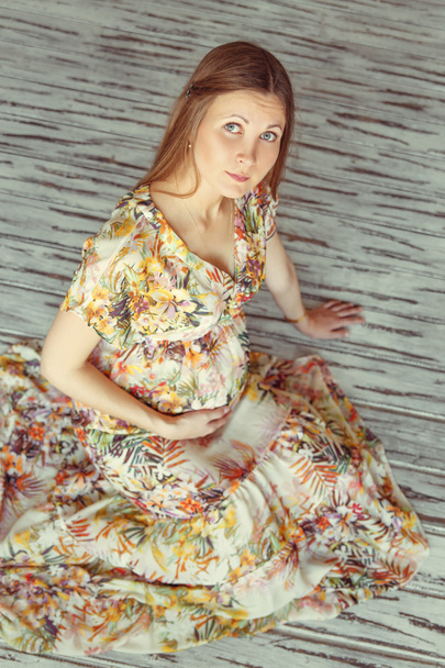 беременная женщина в платье сидит на полу
  - Фото, изображение