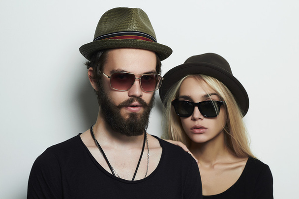 beautiful couple in hat wearing trendy glasses together. Hipster boy and girl. Bearded young man and blonde model in sunglasses - Valokuva, kuva