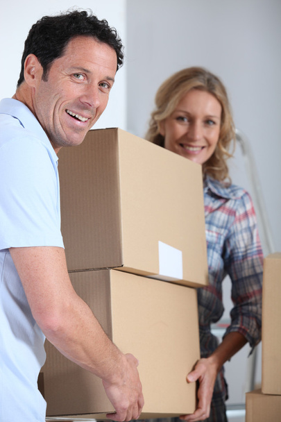 Couple moving a pile of large cardboard boxes - Foto, imagen