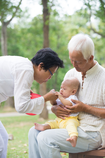 Бабушка и дедушка из Азии играют с внучкой
 - Фото, изображение