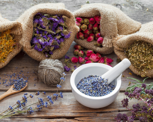 Healing herbs in hessian bags and mortar with dry lavender - Фото, изображение