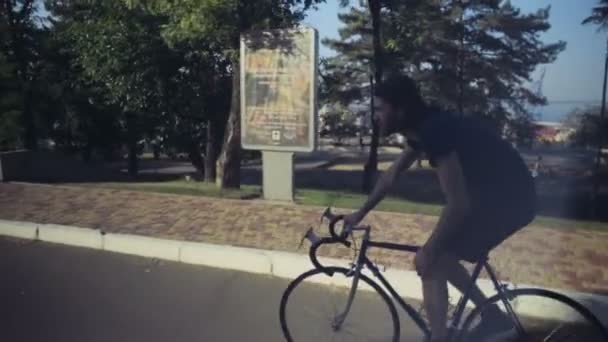 młody przystojny mężczyzna jeździ rowerem w parku zwolnionym tempie - Materiał filmowy, wideo