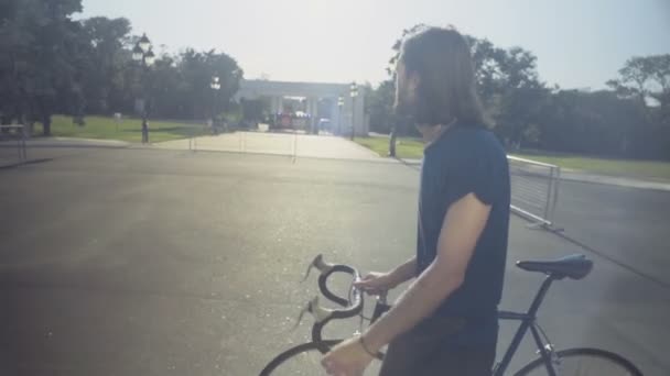 joven hombre guapo va con la bicicleta a través del parque de cámara lenta
 - Imágenes, Vídeo