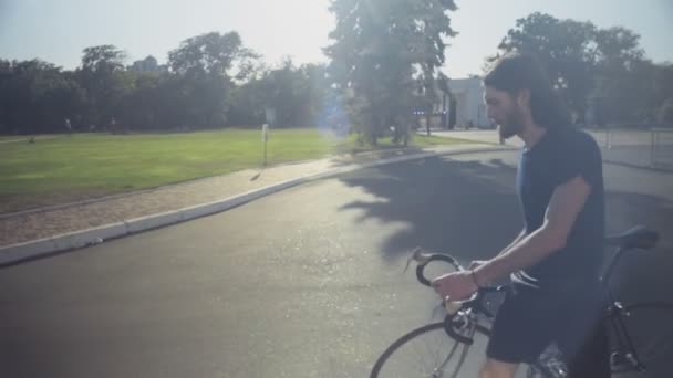 Junger schöner Mann fährt mit dem Fahrrad in Zeitlupe durch den Park - Filmmaterial, Video