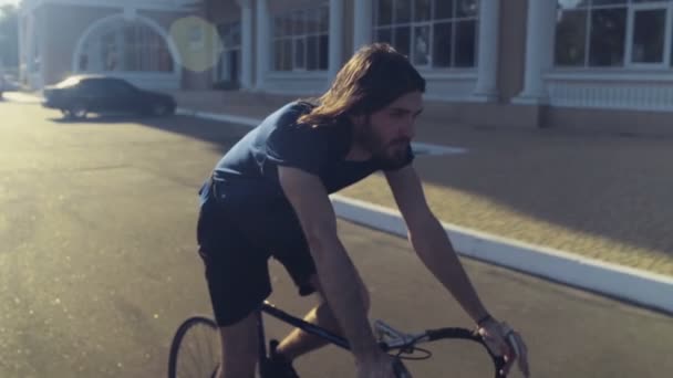 jonge knappe man rijdt een fiets in de straat slow motion - Video