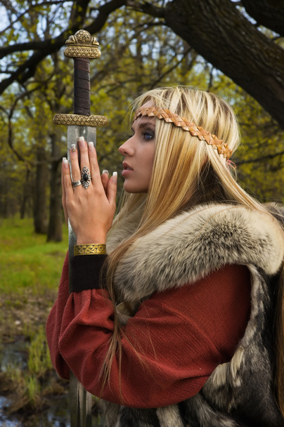 Viking girl with sword in a wood - 写真・画像